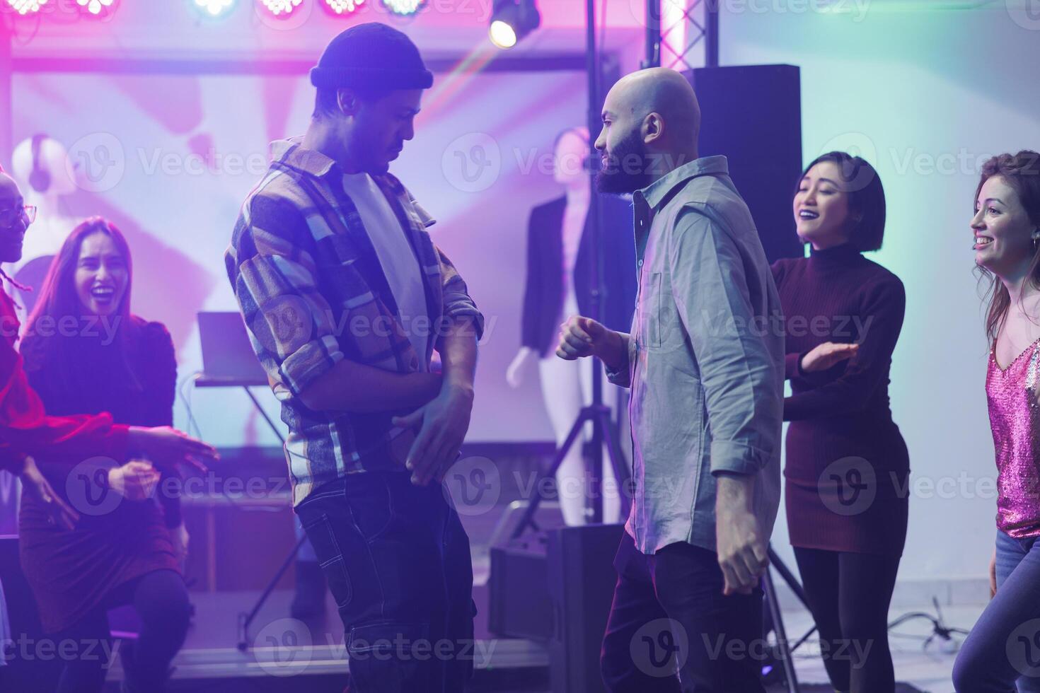 Friends improvising breakdance battle while partying at discotheque in nightclub. Caucasian and arab men dancing, having fun and showing moves on dancefloor while relaxing in club photo