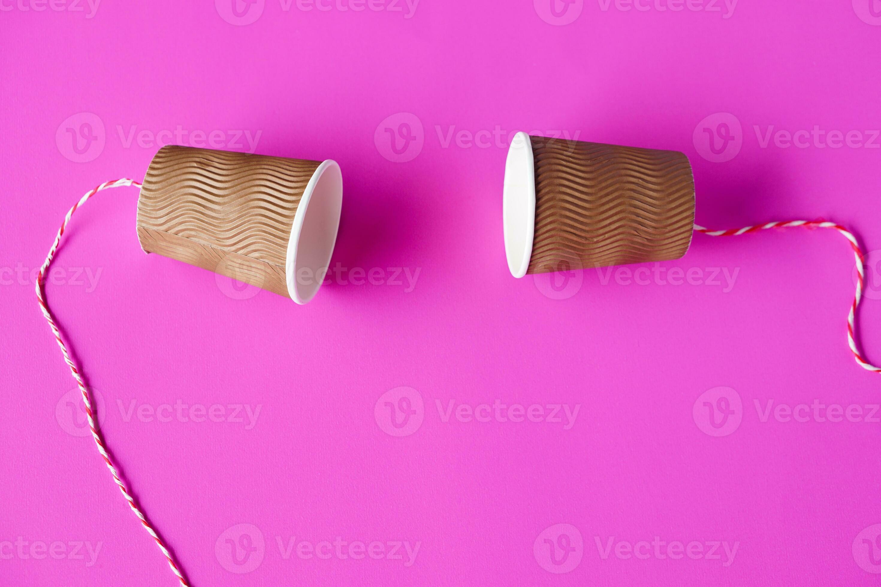 DIY paper cups with string on pink background. Concept, telephone toys