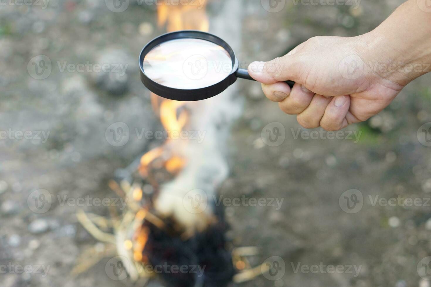 Close up hand held magnifying glass to make fire for burning dried hays.Concept, Science experiment about convex lens, hold magnifying glass between the sun and tinder. Handy survival skill photo