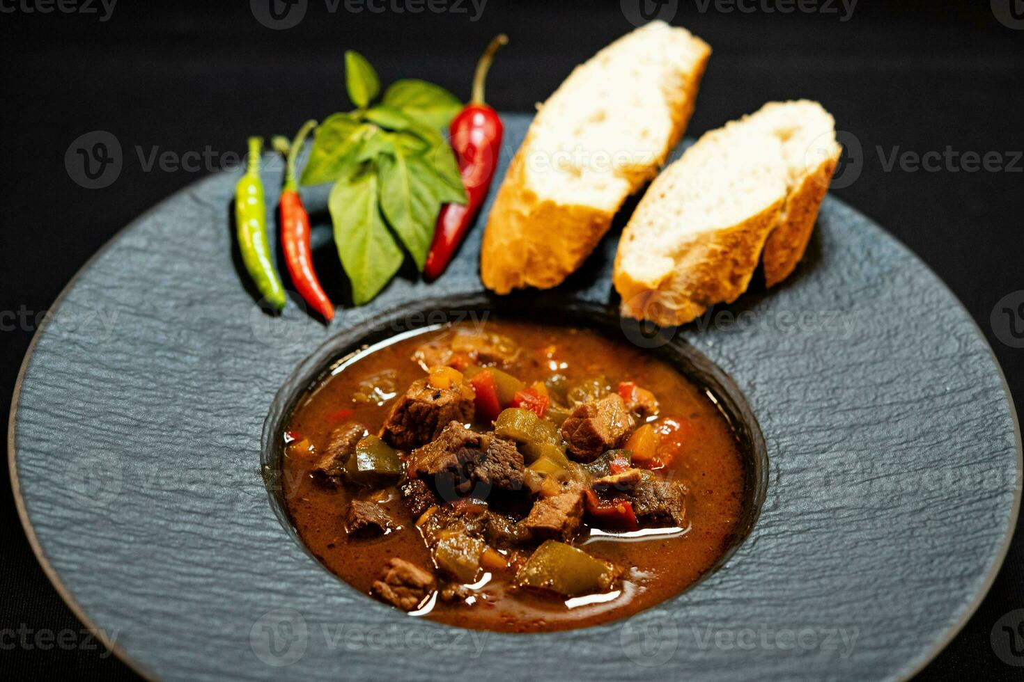 traditional Hungarian food beef goulash with bread an spicy peppers photo