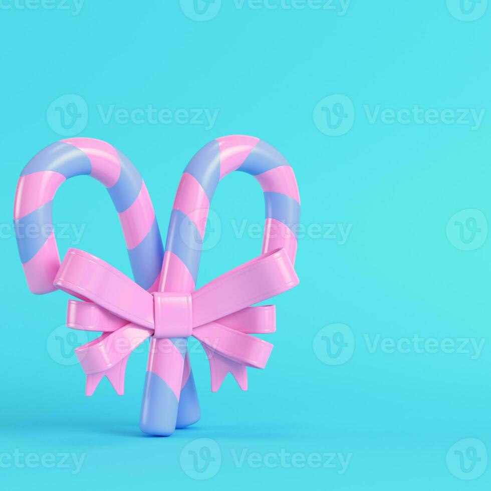 Pink christmas candy canes with a bow on bright blue background in pastel colors photo