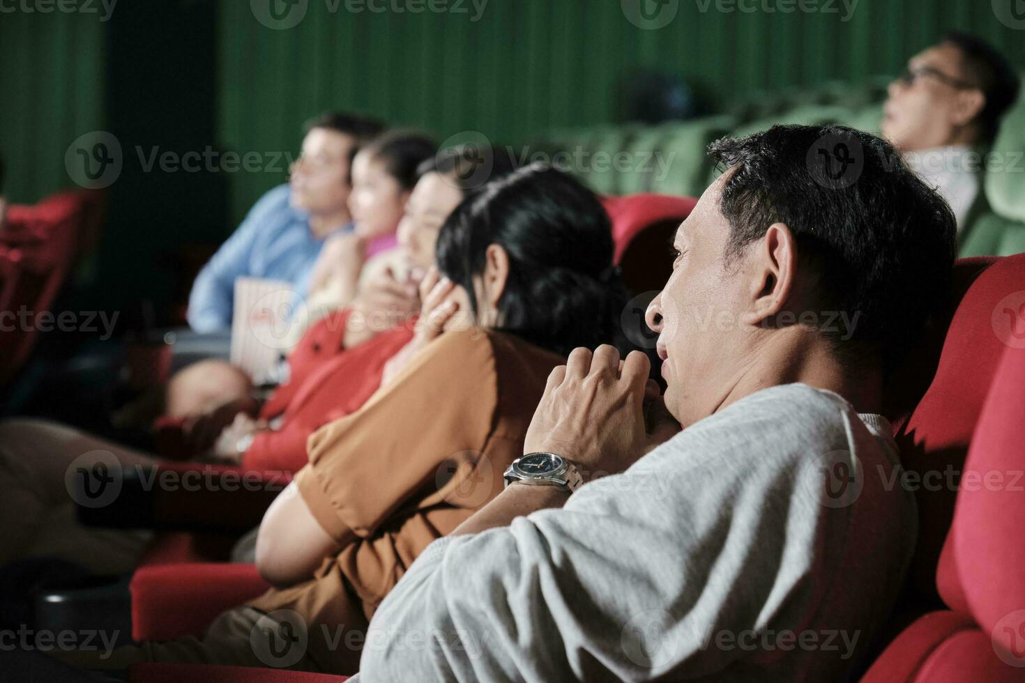 Various people in theater. Asian man and many audiences are scared of watching thriller and horror cinema, frightened together on movie stage, and entertainment lifestyle with film show on weekend. photo