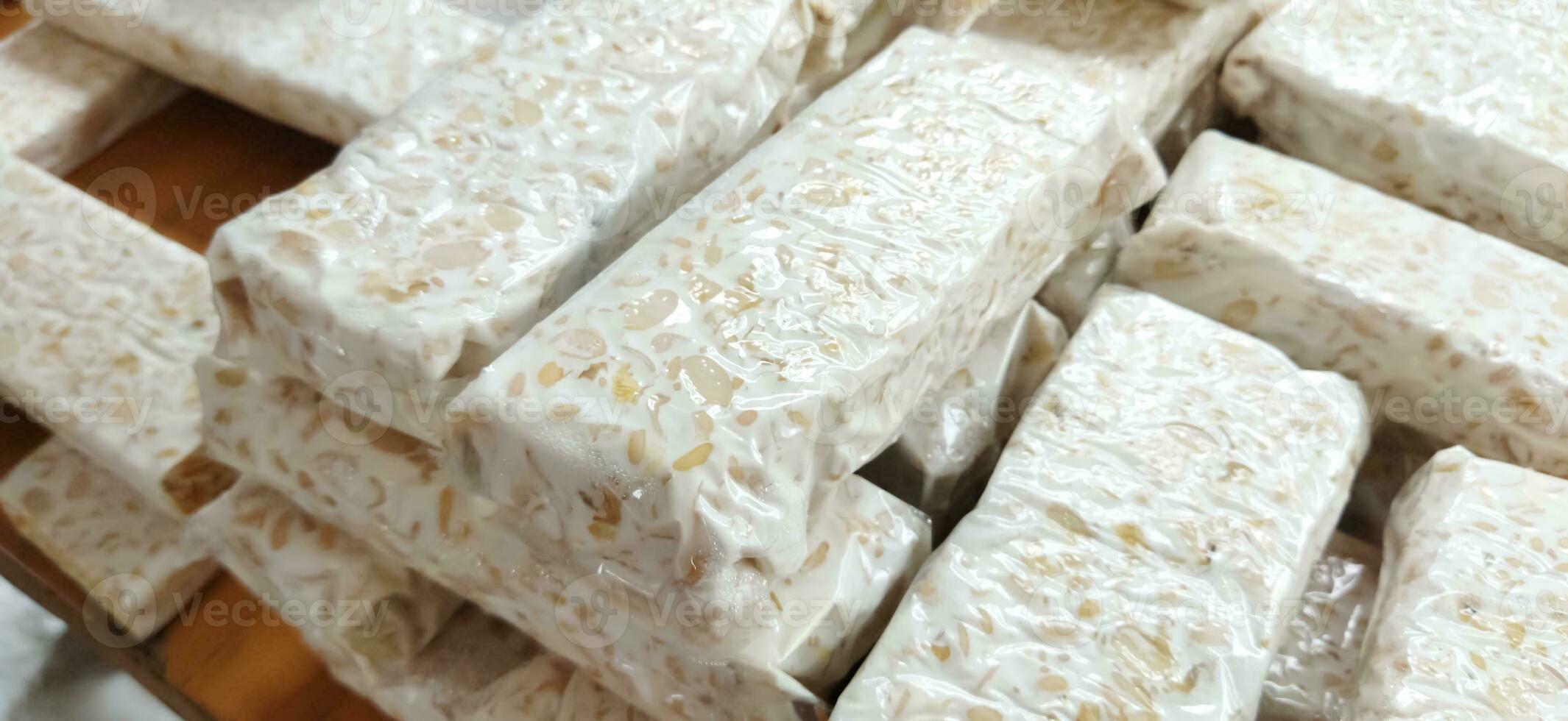 tempe mentah or raw tempeh, uncooked soybean cake from indonesia in a plastic on the table photo