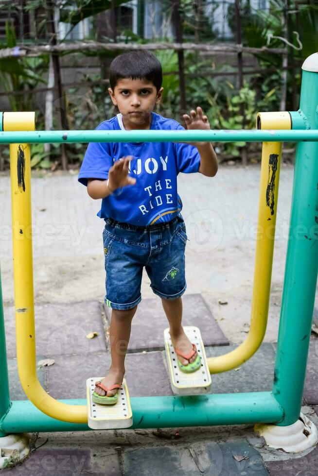 Asian boy doing routine exercise in society park during the morning time. Cute little kid exercise and gym to keep himself fit for life. Child exercise outdoor shoot photo