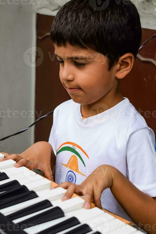 Asian boy playing the synthesizer or piano. Cute little kid learning how to play piano. Child's hands on the keyboard indoor. photo