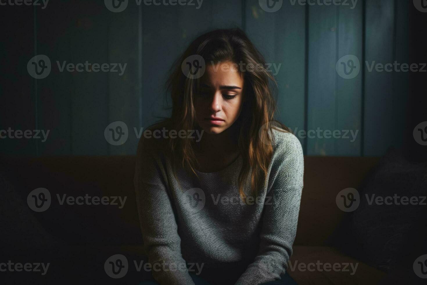 Depressed young woman in dimly lit room background with empty space for text photo