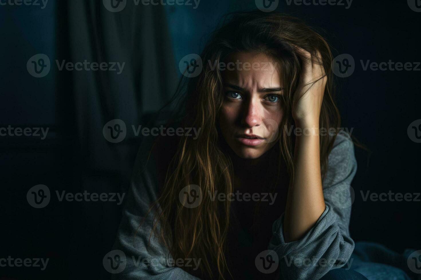 Young woman portraying intense emotional distress in dimly lit solitude photo