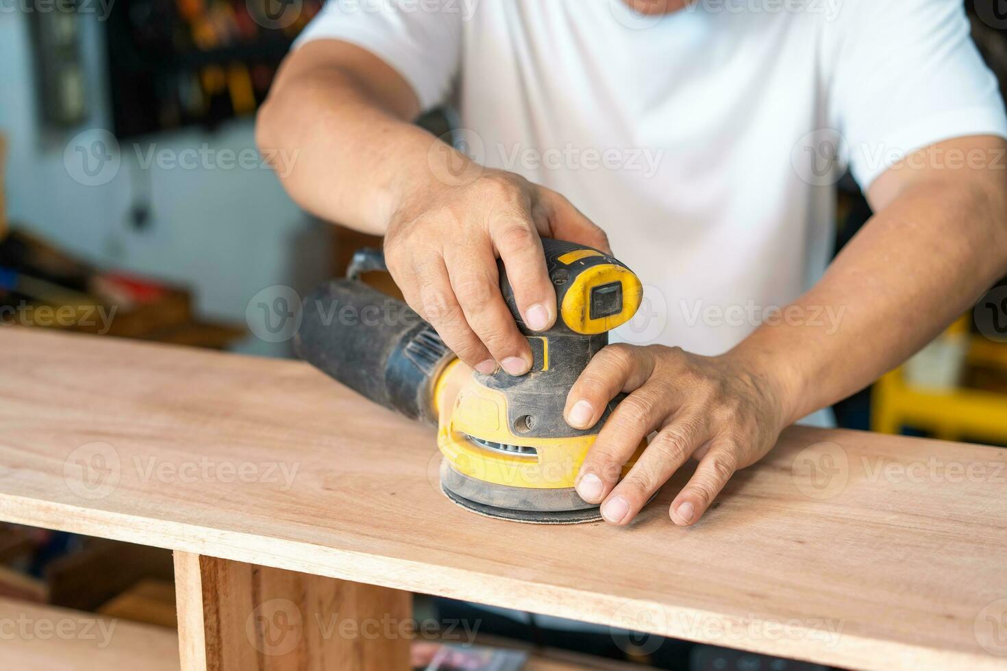 carpenter using a random orbit sander on wood in the workshop,woodworking concept , selective focus photo