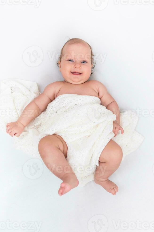 linda contento bebé mentiras en un blanco sábana y es cubierto con un de lana paño foto