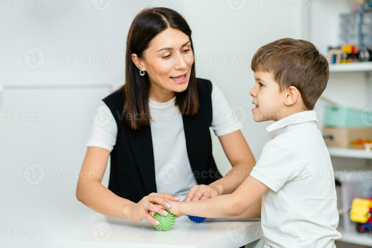 un mujer habla terapeuta ofertas con el niño y enseña él el correcto pronunciación y competente discurso. foto
