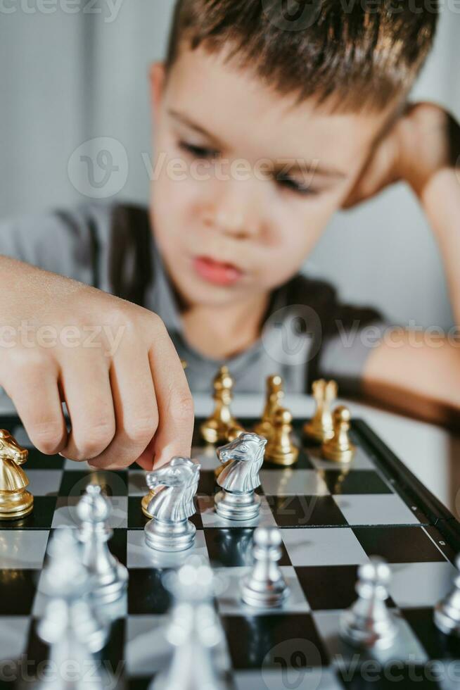 Cute boy 5 years old plays chess by himself in his room at home photo