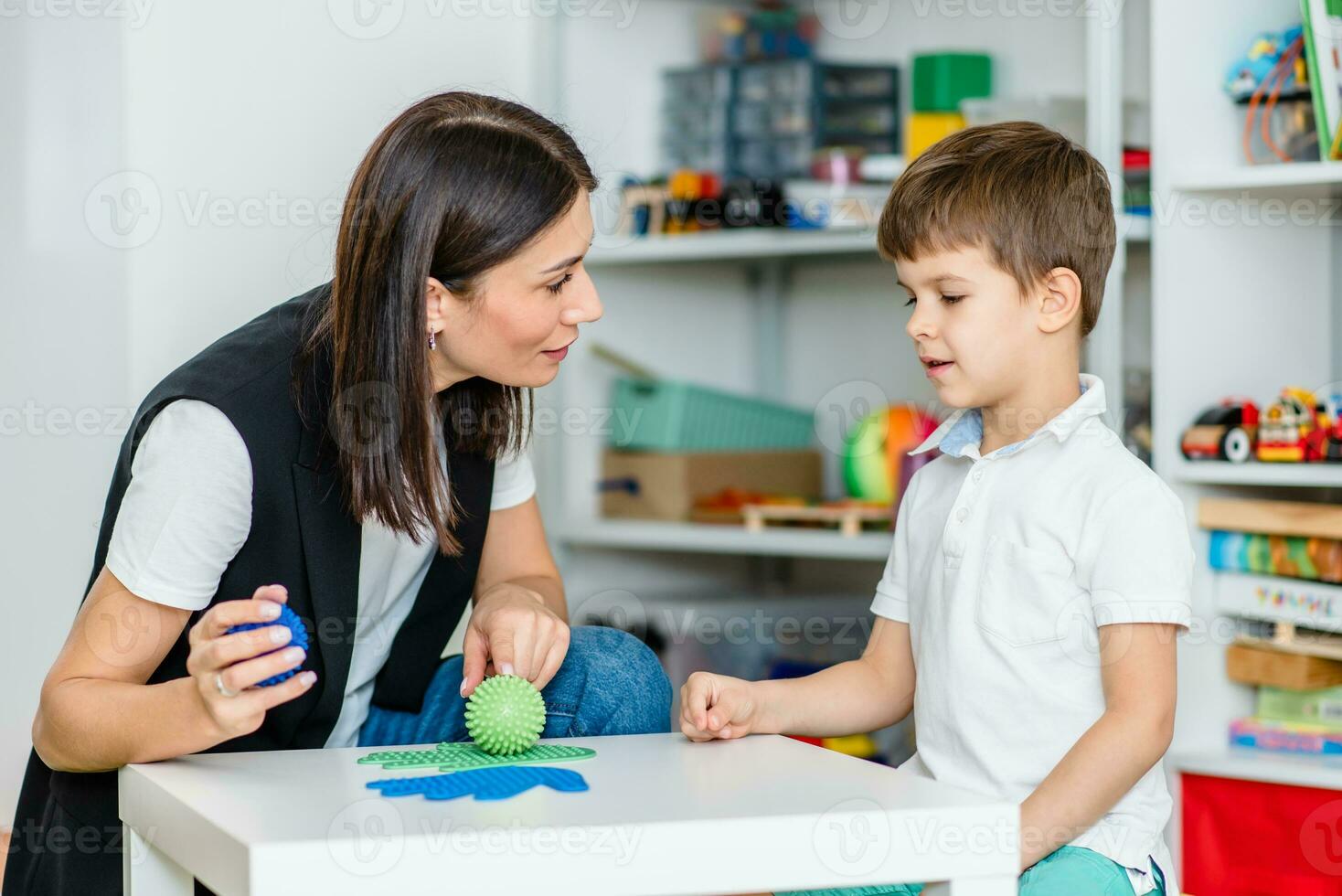 un mujer habla terapeuta ofertas con el niño y enseña él el correcto pronunciación y competente discurso. foto