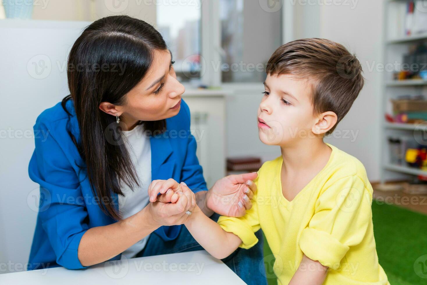 A woman speech therapist deals with the child and teaches him the correct pronunciation and competent speech. photo