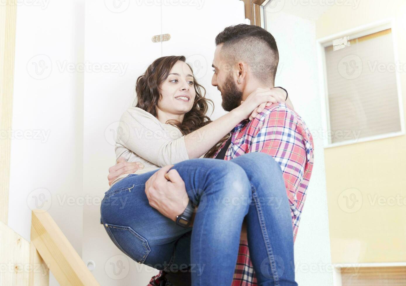 young man holding his girlfriend in his arms after moving photo