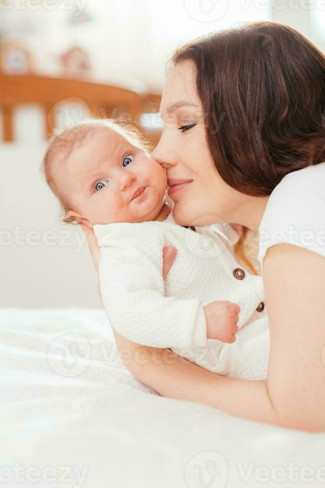 Portrait of a young woman kissing her little baby daughter photo