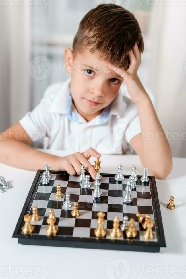 Smart boy learns to play chess by himself in his room at home photo