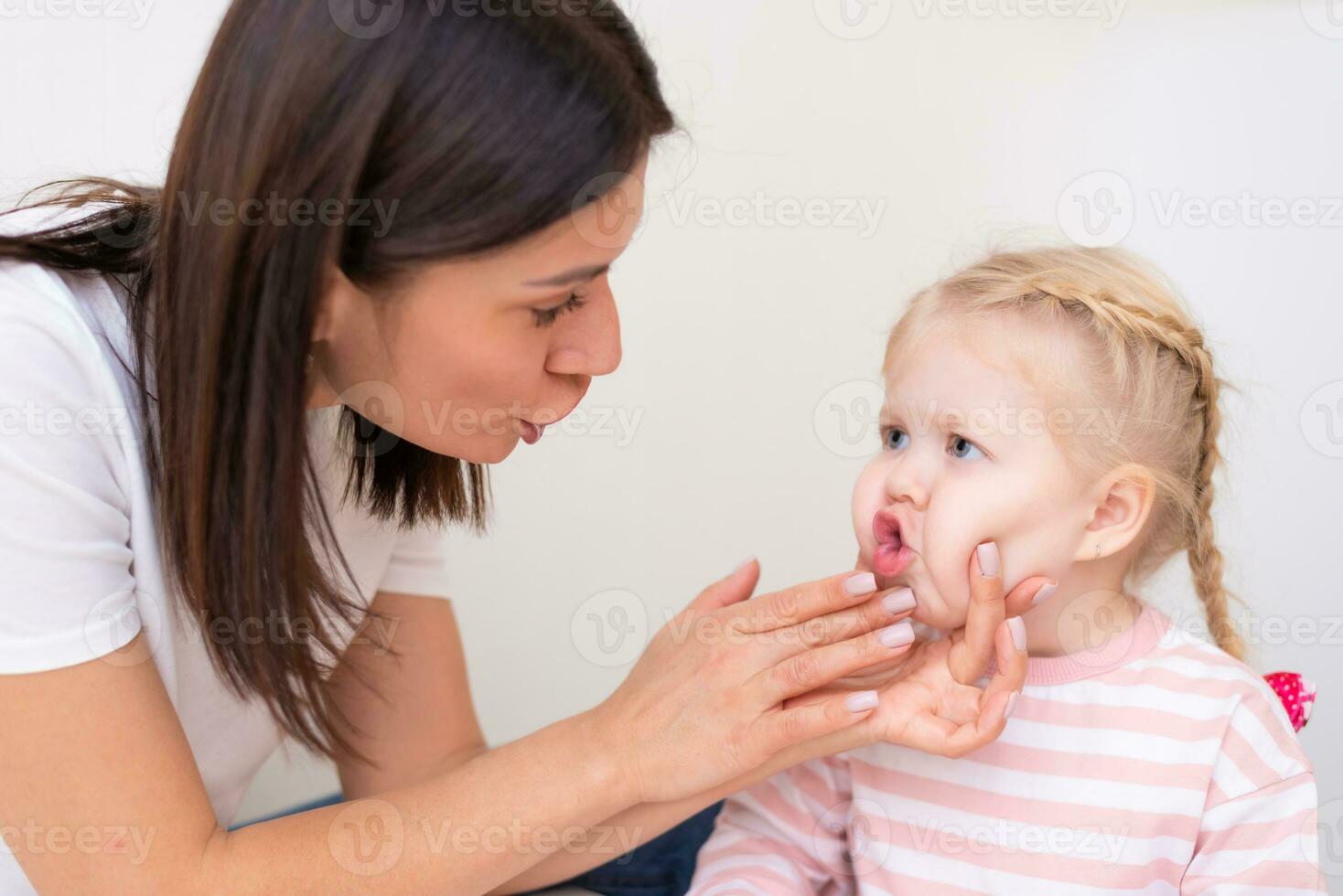 Woman speech therapist helps cute girl to learn correct pronunciation and literate speech photo