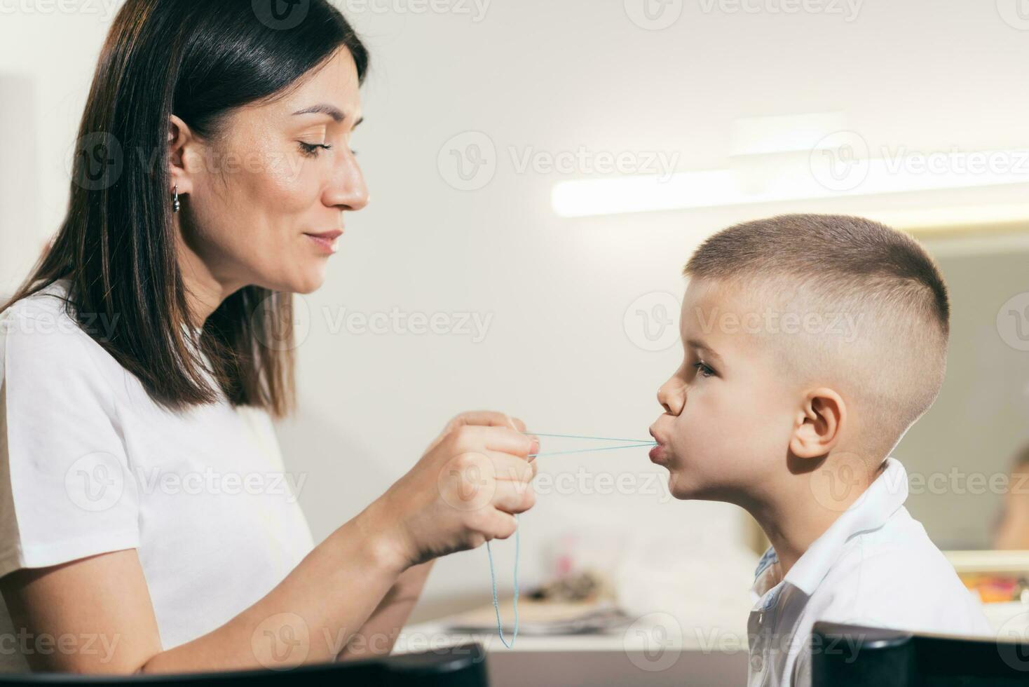 Woman speech therapist helps a boy correct the violation of his speech photo