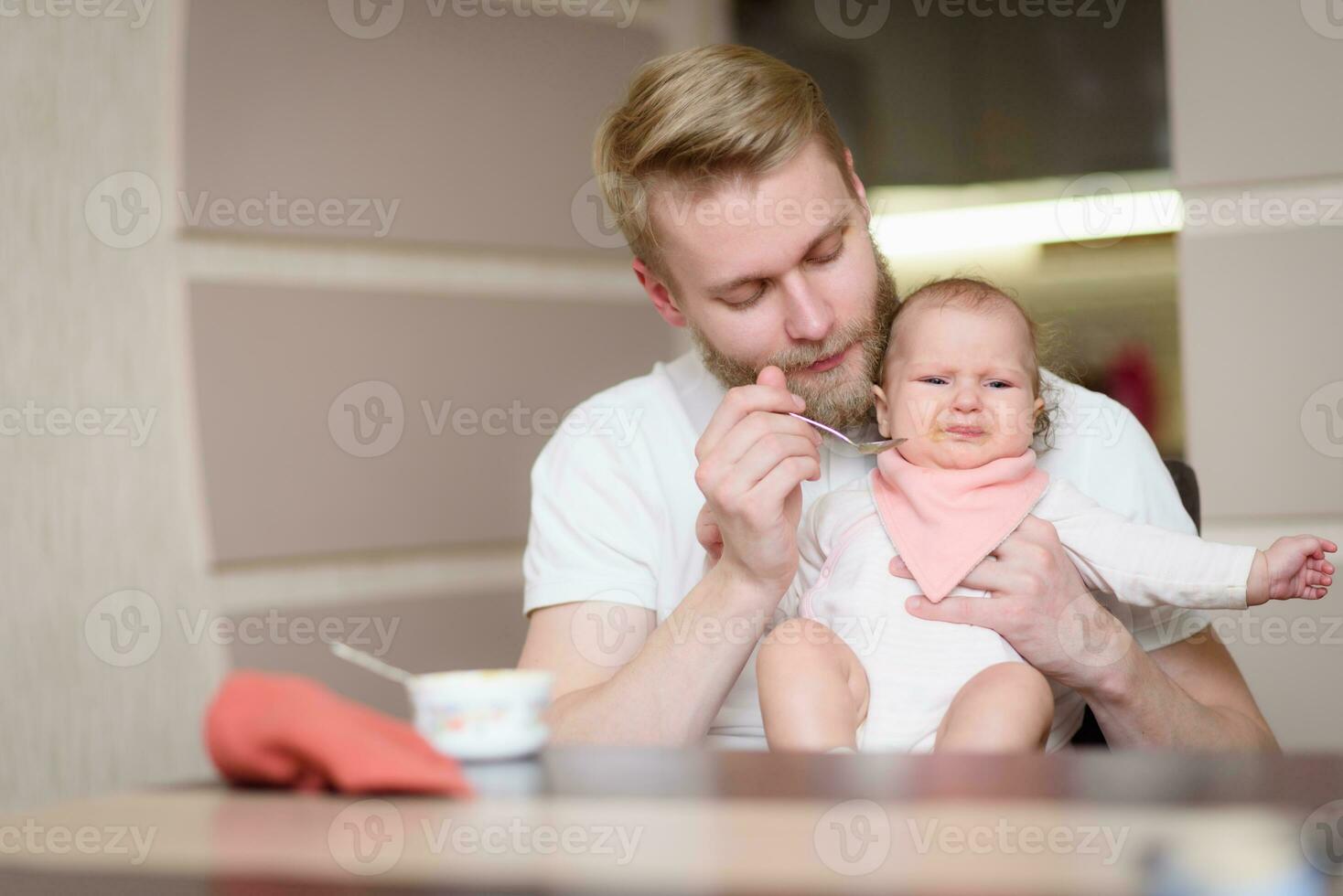 Father feeds his naughty little daughter who refuses to eat complementary foods photo