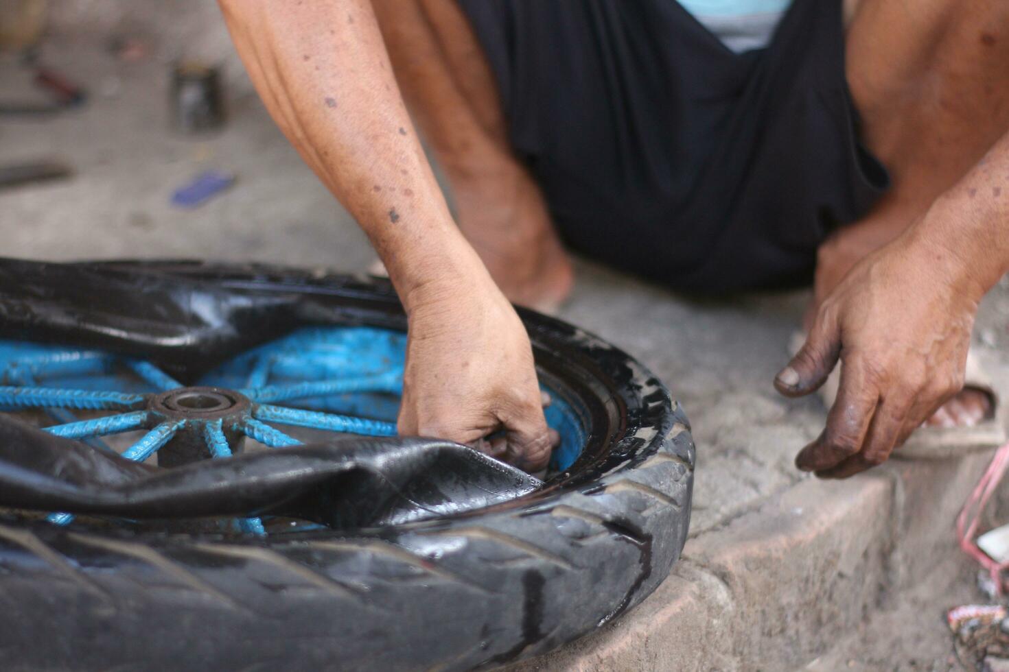 An Indonesian service worker is changing the tire of a bicycle cart manually photo