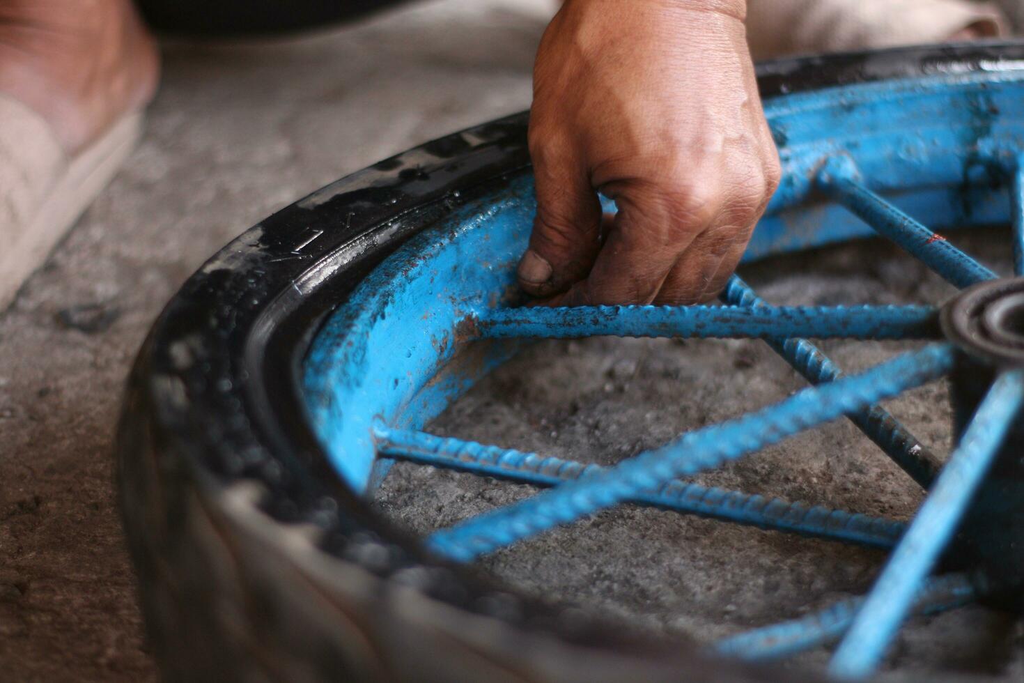 An Indonesian service worker is changing the tire of a bicycle cart manually photo