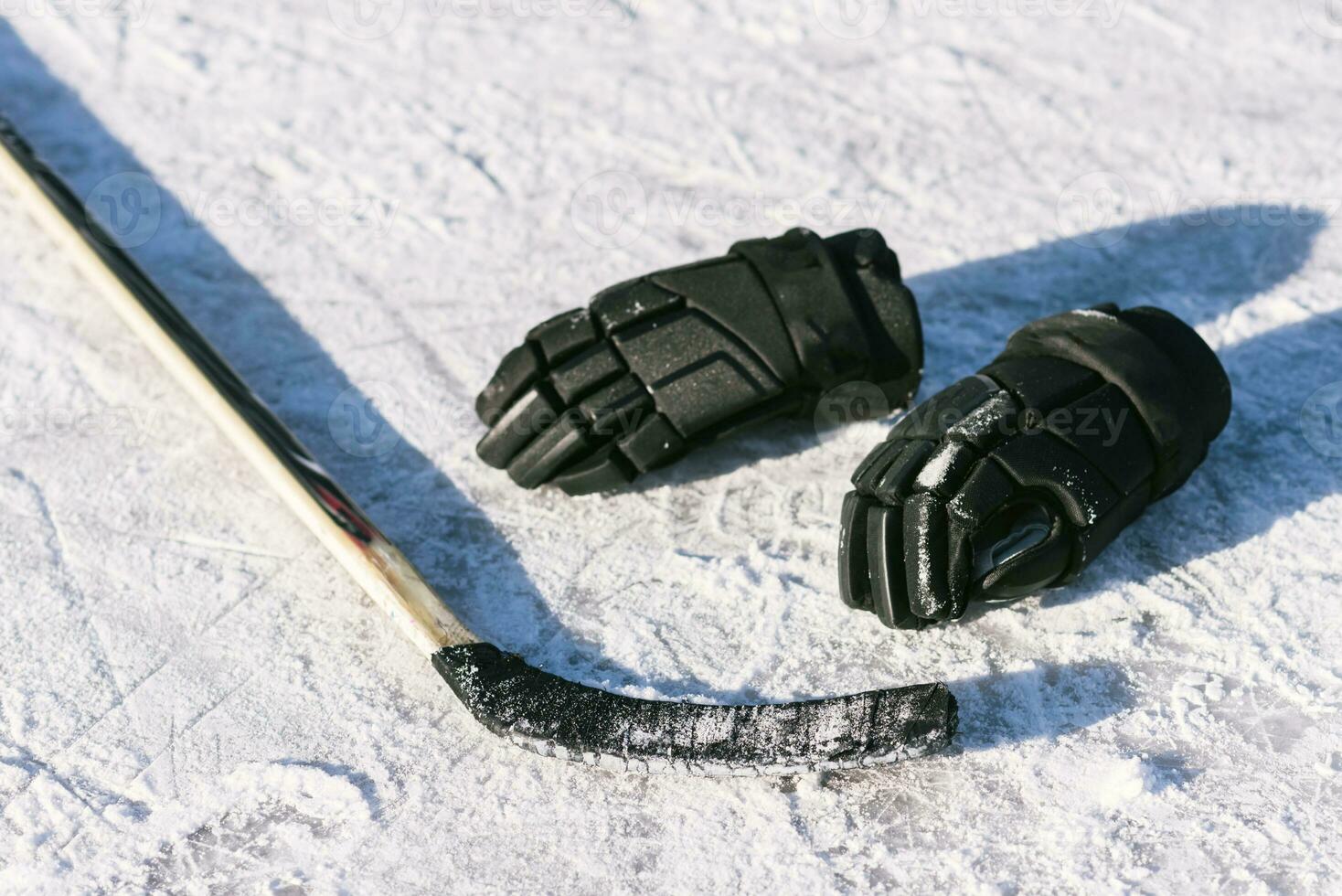 The gloves and hockey stick lay on the snow photo