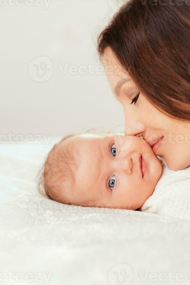 Portrait of a young woman kissing her little baby daughter photo