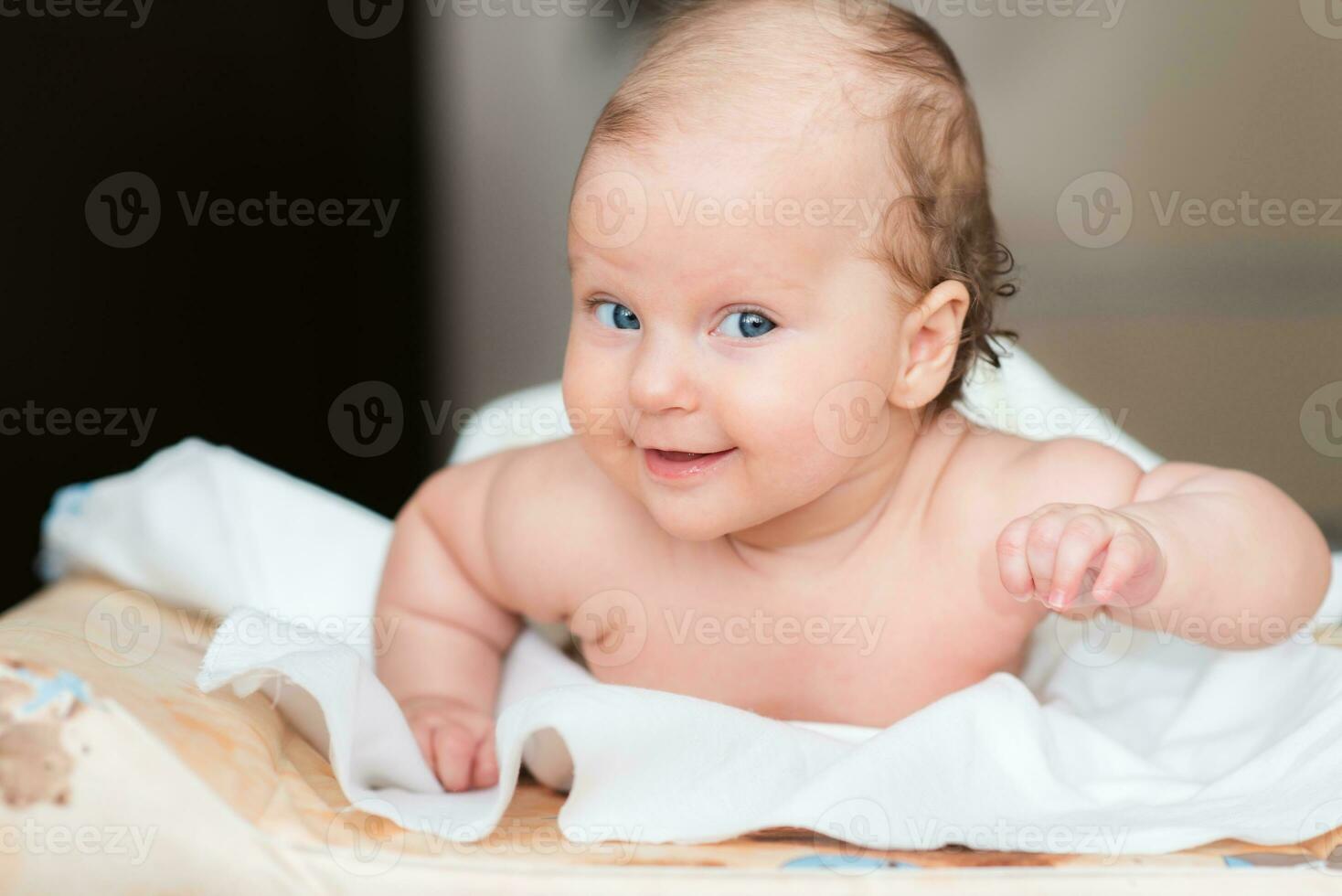 Portrait of a beautiful baby girl lies on a white sheet in her room photo