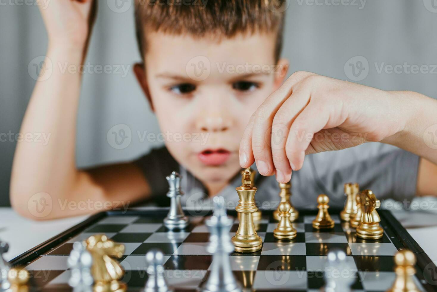 Smart boy learns to play chess by himself in his room at home photo