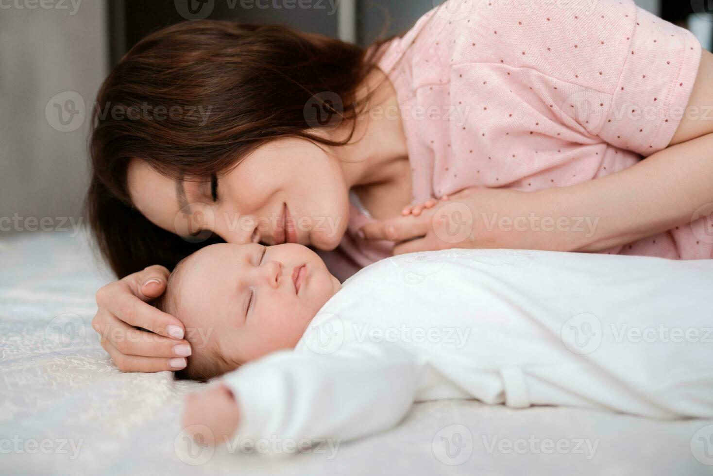 Young woman taking care of her sleeping baby daughter in the bedroom photo