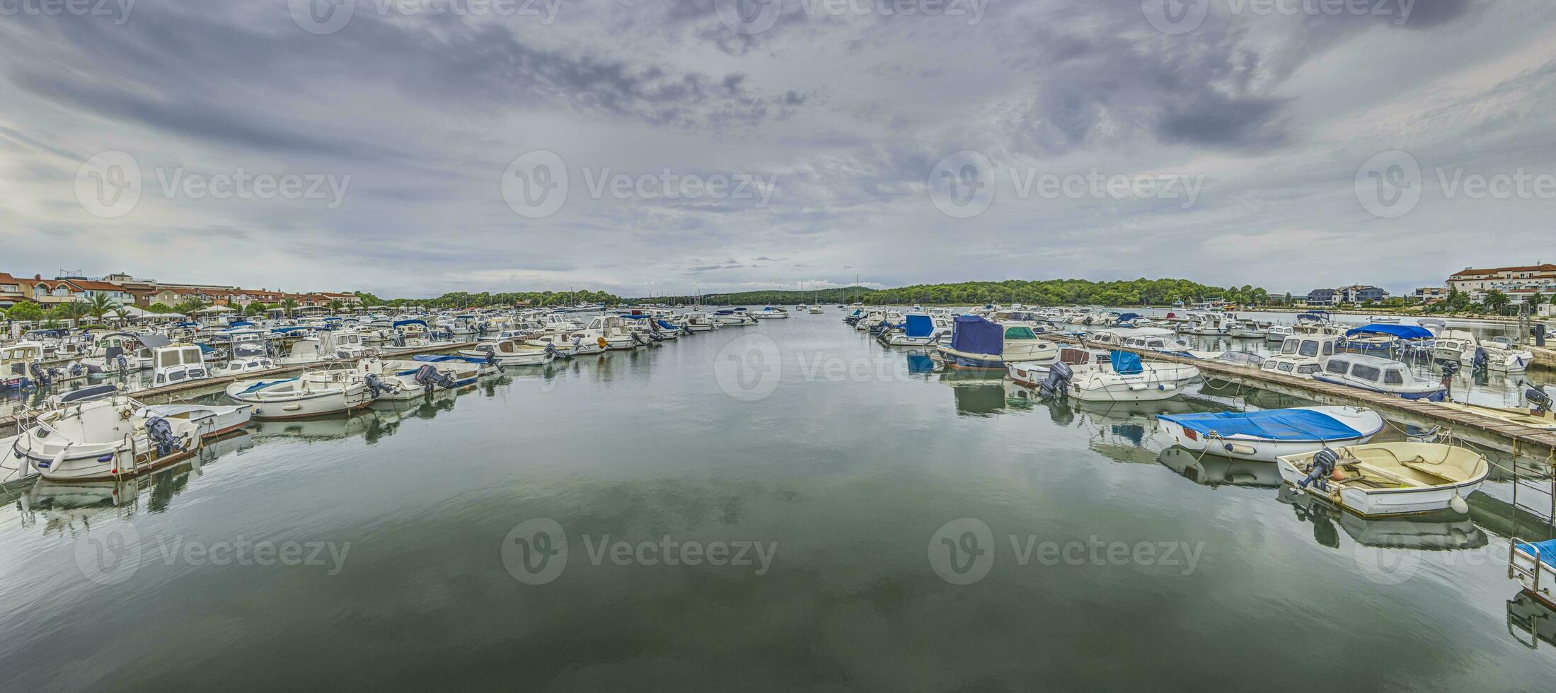 View over a yacht harbor with docked ships in front of clouded sky photo