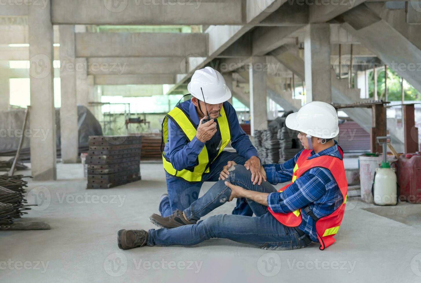 un del trabajador piernas estaba lesionado a sitio, un colega rescatado él desde accidente y utilizando walkie-talkie a llamada primero ayuda concepto de equipo riesgo gestión, la seguridad a accidente laboral en sitio trabajo foto