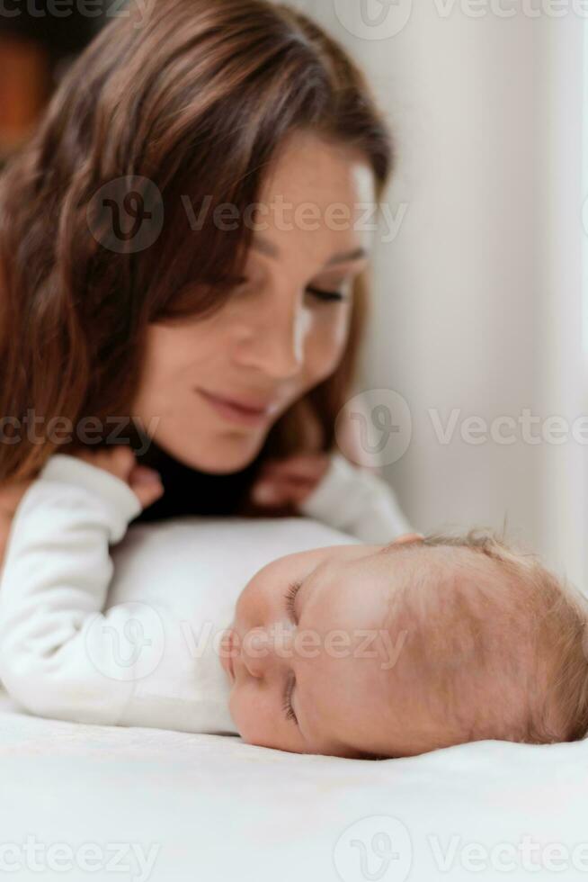 Young woman taking care of her sleeping baby daughter in the bedroom photo