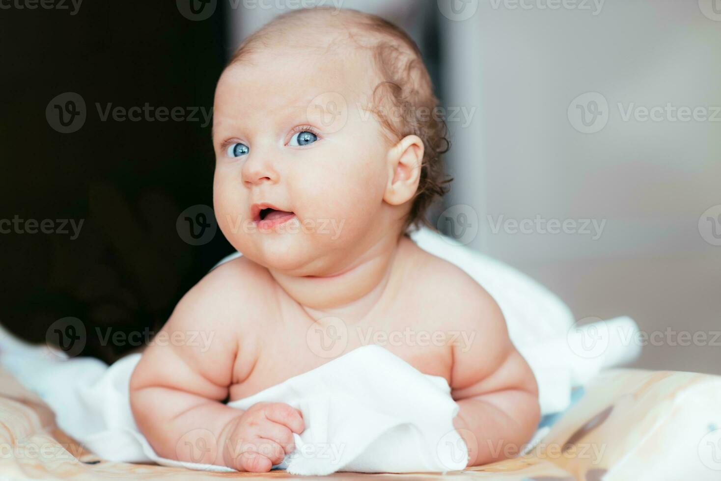 Happy baby girl lies on a white sheet in her room photo