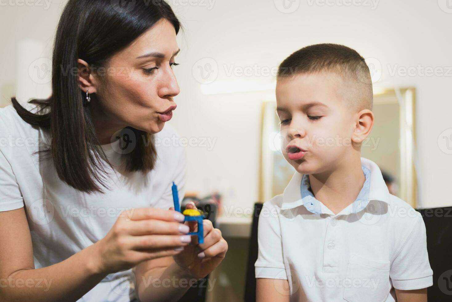 un mujer habla terapeuta ofertas con el niño y enseña él el correcto pronunciación y competente discurso. foto