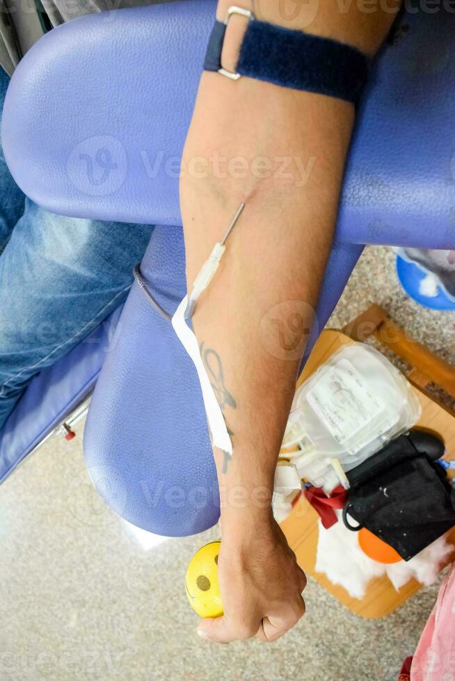 donante de sangre en el campamento de donación de sangre sostenido con una pelota hinchable en la mano en el templo balaji, vivek vihar, delhi, india, imagen para el día mundial del donante de sangre el 14 de junio de cada año, campamento de donación de sangre foto