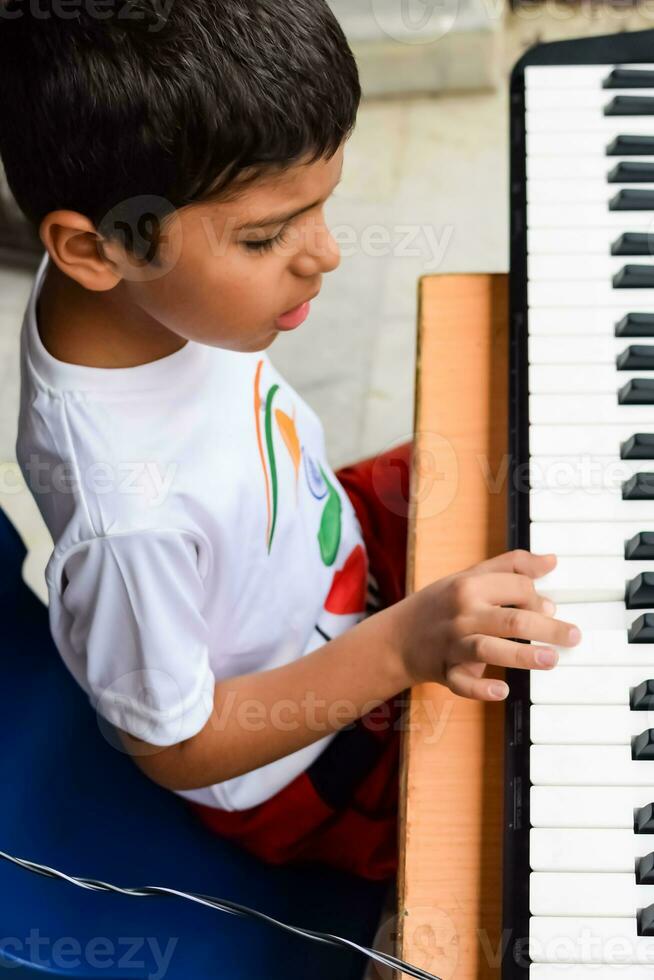 Asian boy playing the synthesizer or piano. Cute little kid learning how to play piano. Child's hands on the keyboard indoor. photo