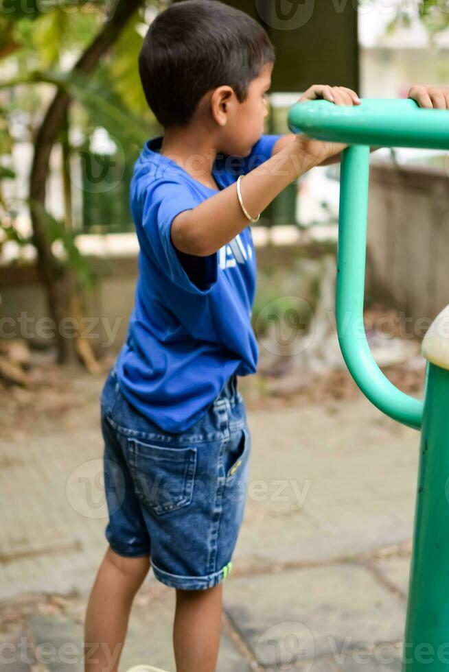 asiático chico haciendo rutina ejercicio en sociedad parque durante el Mañana tiempo. linda pequeño niño ejercicio y gimnasio a mantener él mismo ajuste para vida. niño ejercicio al aire libre disparar foto