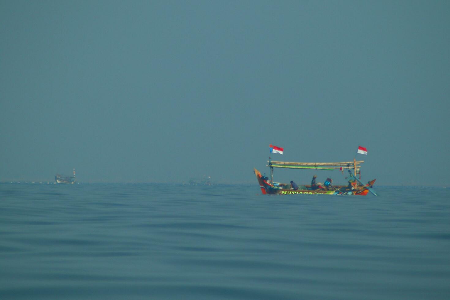 passenger ships and fishing boats, equally visible above the vast ocean. against a background of blue sea and blue clouds. photo