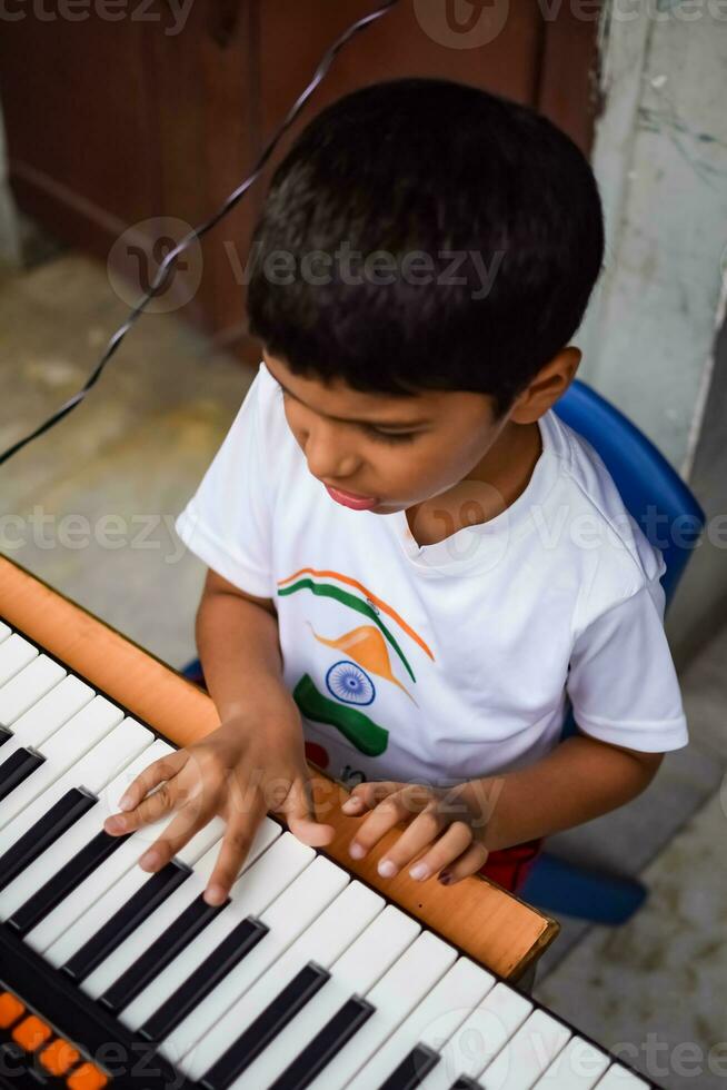 Asian boy playing the synthesizer or piano. Cute little kid learning how to play piano. Child's hands on the keyboard indoor. photo