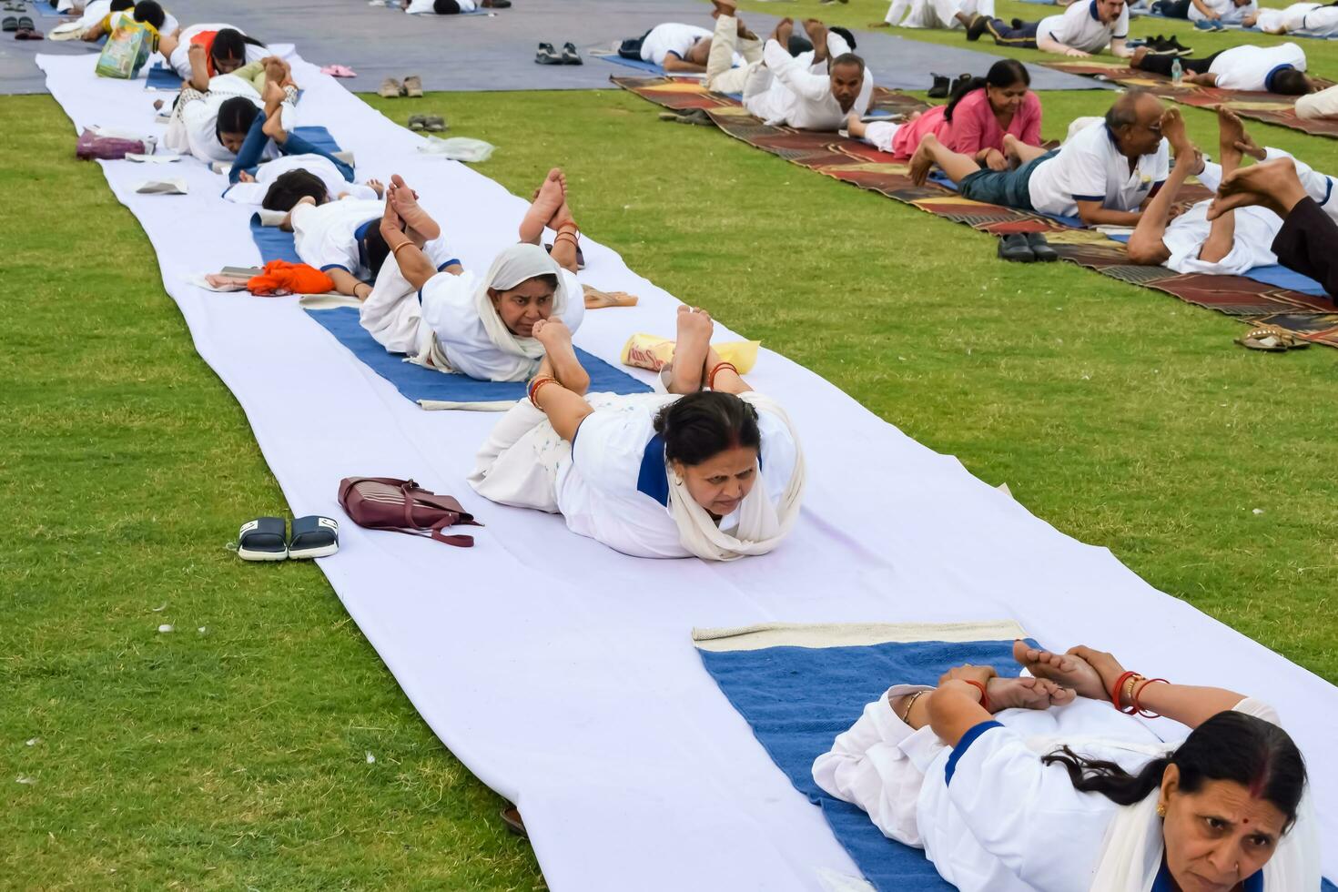 New Delhi, India, June 21, 2023 - Group Yoga exercise session for people at Yamuna Sports Complex in Delhi on International Yoga Day, Big group of adults attending yoga class in cricket stadium photo
