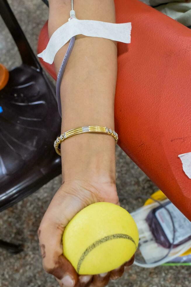 Blood donor at Blood donation camp held with a bouncy ball holding in hand at Balaji Temple, Vivek Vihar, Delhi, India, Image for World blood donor day on June 14 every year, Blood Donation Camp photo