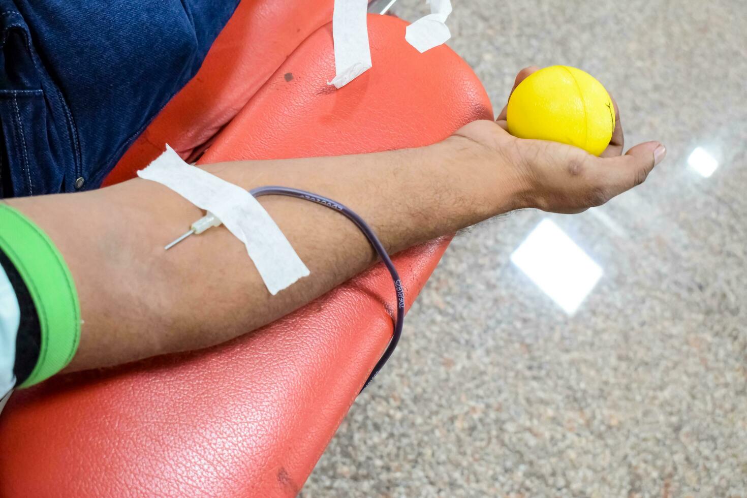 Blood donor at Blood donation camp held with a bouncy ball holding in hand at Balaji Temple, Vivek Vihar, Delhi, India, Image for World blood donor day on June 14 every year, Blood Donation Camp photo