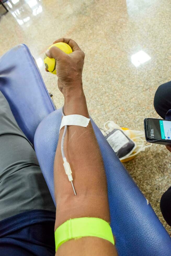 Blood donor at Blood donation camp held with a bouncy ball holding in hand at Balaji Temple, Vivek Vihar, Delhi, India, Image for World blood donor day on June 14 every year, Blood Donation Camp photo