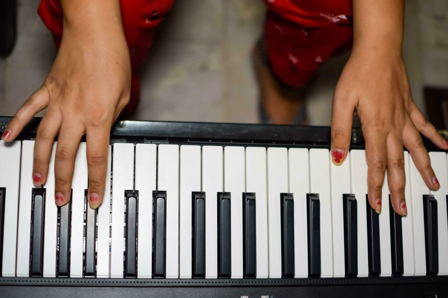 Asian boy playing the synthesizer or piano. Cute little kid learning how to play piano. Child's hands on the keyboard indoor. photo