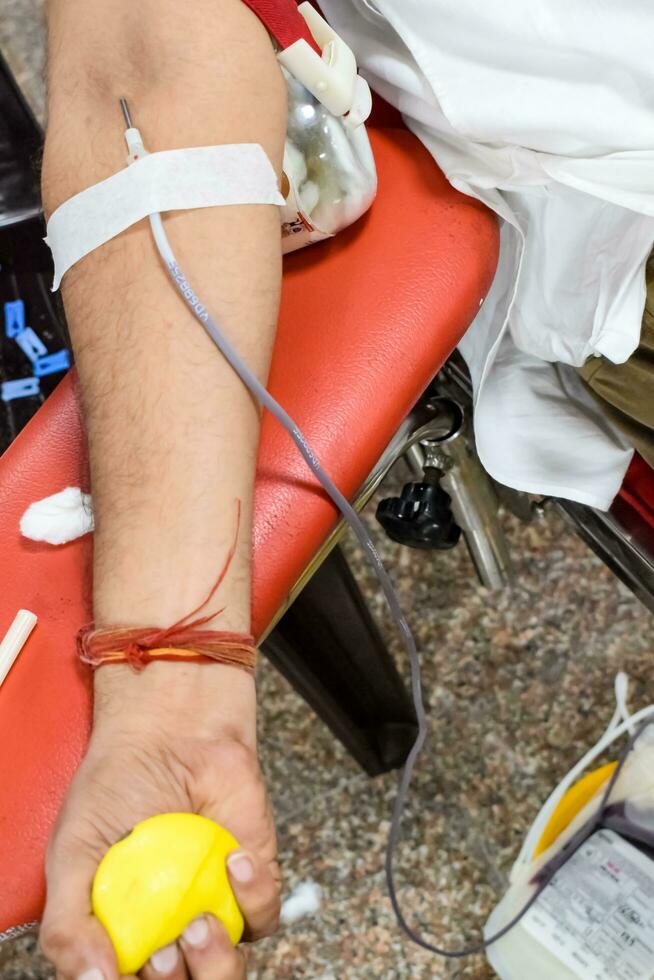Blood donor at Blood donation camp held with a bouncy ball holding in hand at Balaji Temple, Vivek Vihar, Delhi, India, Image for World blood donor day on June 14 every year, Blood Donation Camp photo