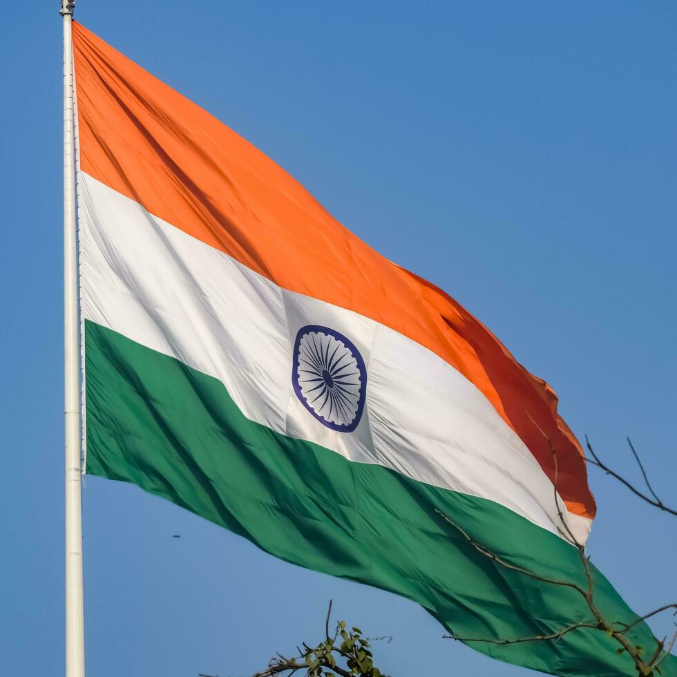 India flag flying high at Connaught Place with pride in blue sky, India flag fluttering, Indian Flag on Independence Day and Republic Day of India, tilt up shot, Waving Indian flag, Har Ghar Tiranga photo