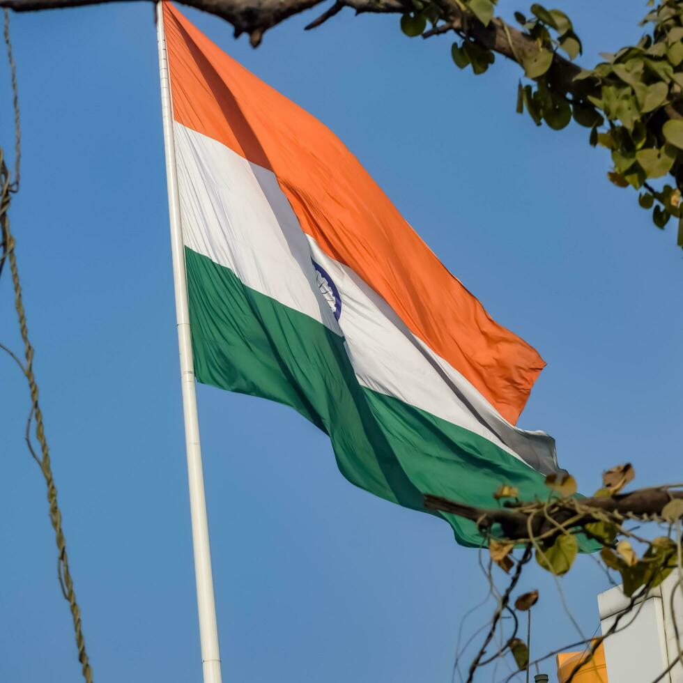 India flag flying high at Connaught Place with pride in blue sky, India flag fluttering, Indian Flag on Independence Day and Republic Day of India, tilt up shot, Waving Indian flag, Har Ghar Tiranga photo