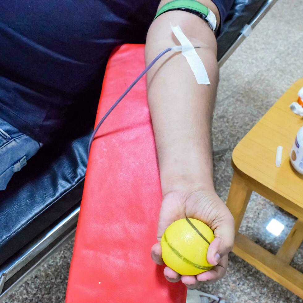 Blood donor at Blood donation camp held with a bouncy ball holding in hand at Balaji Temple, Vivek Vihar, Delhi, India, Image for World blood donor day on June 14 every year, Blood Donation Camp photo