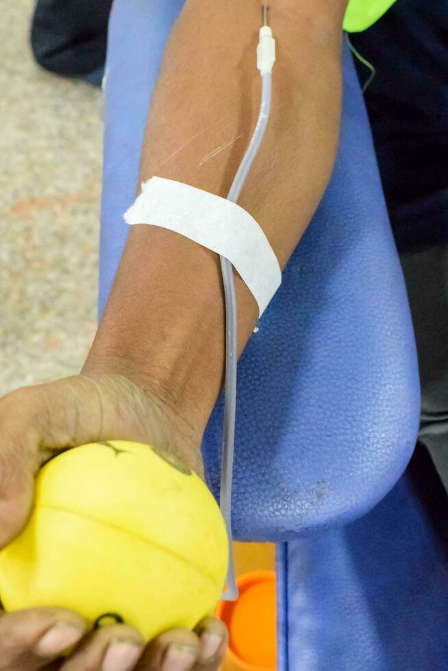 Blood donor at Blood donation camp held with a bouncy ball holding in hand at Balaji Temple, Vivek Vihar, Delhi, India, Image for World blood donor day on June 14 every year, Blood Donation Camp photo